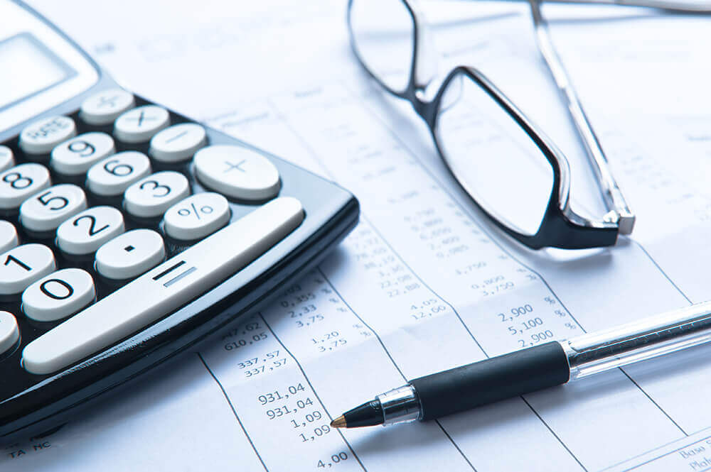 glasses, pen, and calculator lying on a notebook